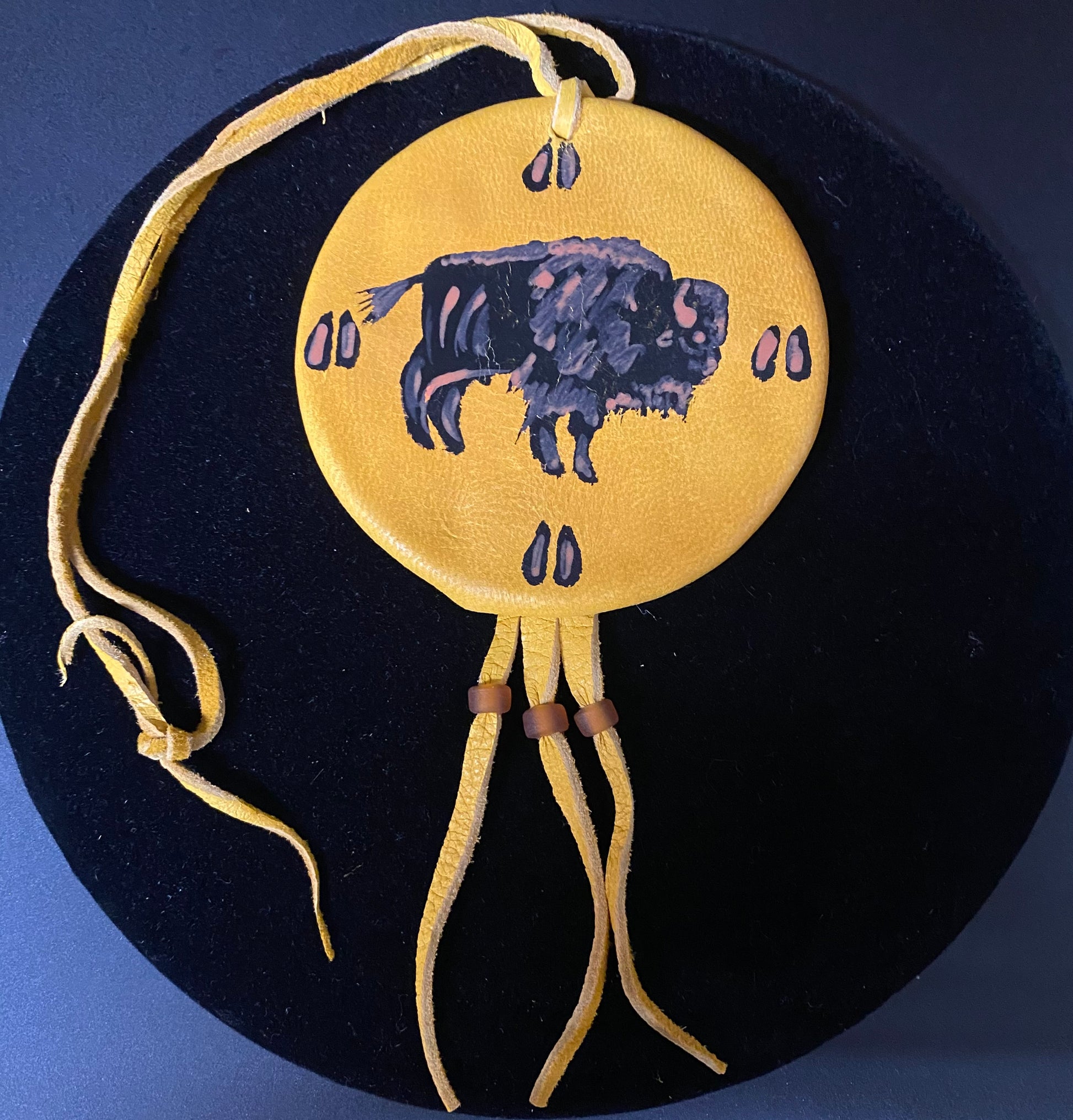 Decorative pendant with a bison design on a dark background