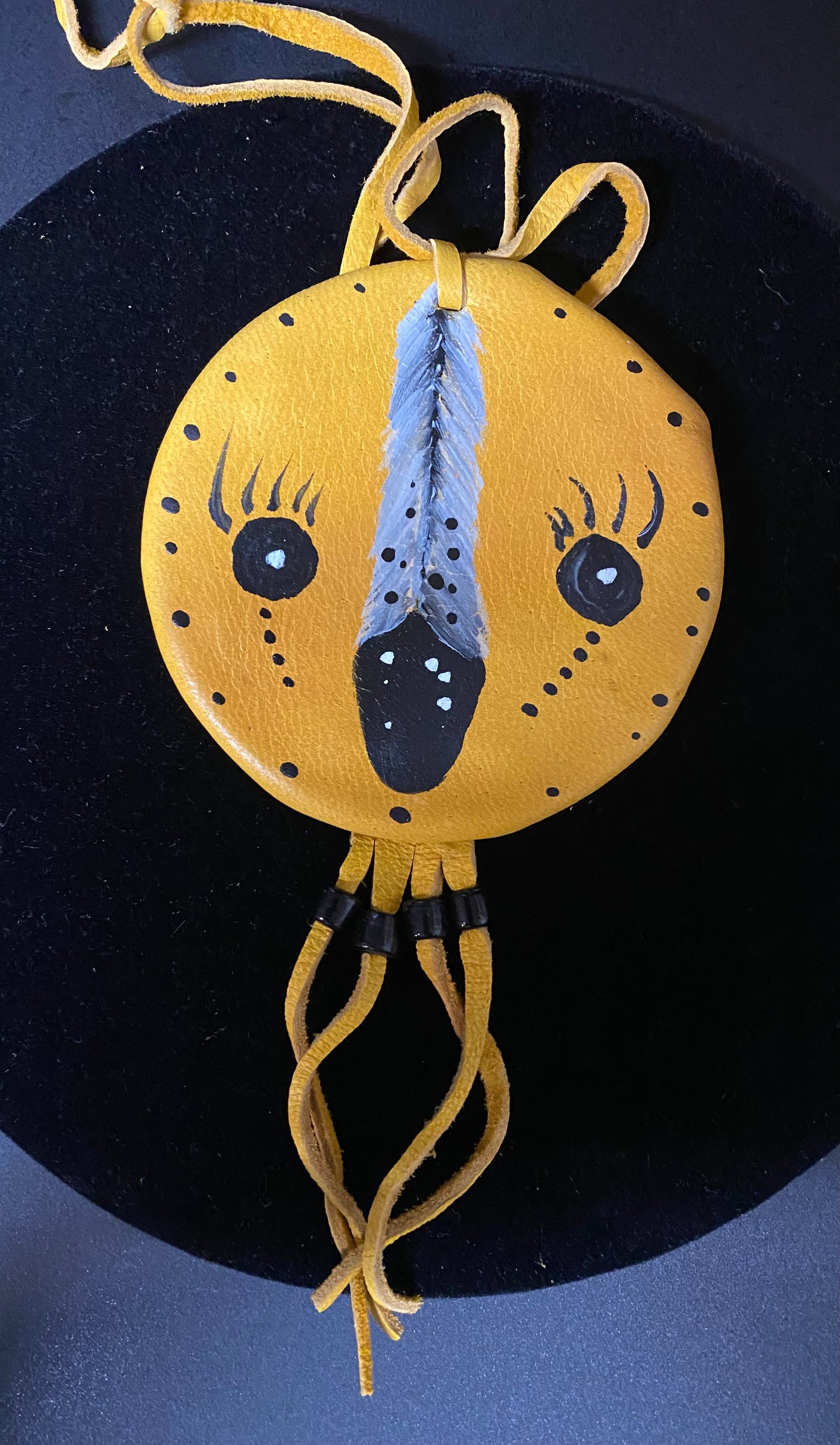 Yellow circular pouch with a face design on a dark background