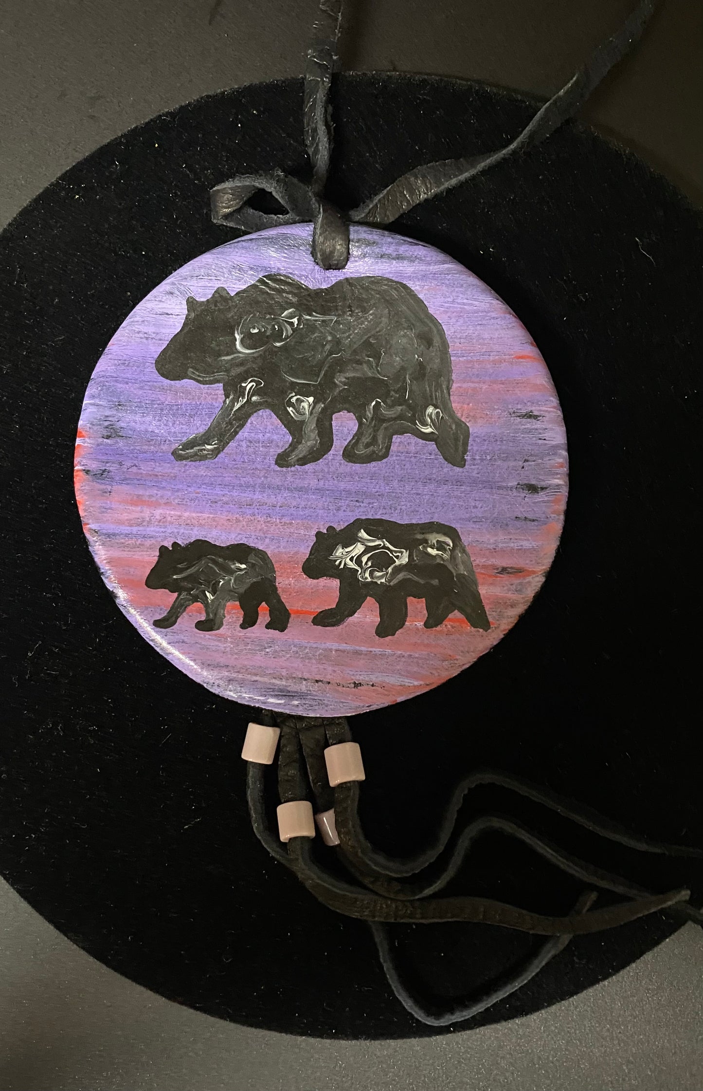 Round pendant with bear designs on a dark background