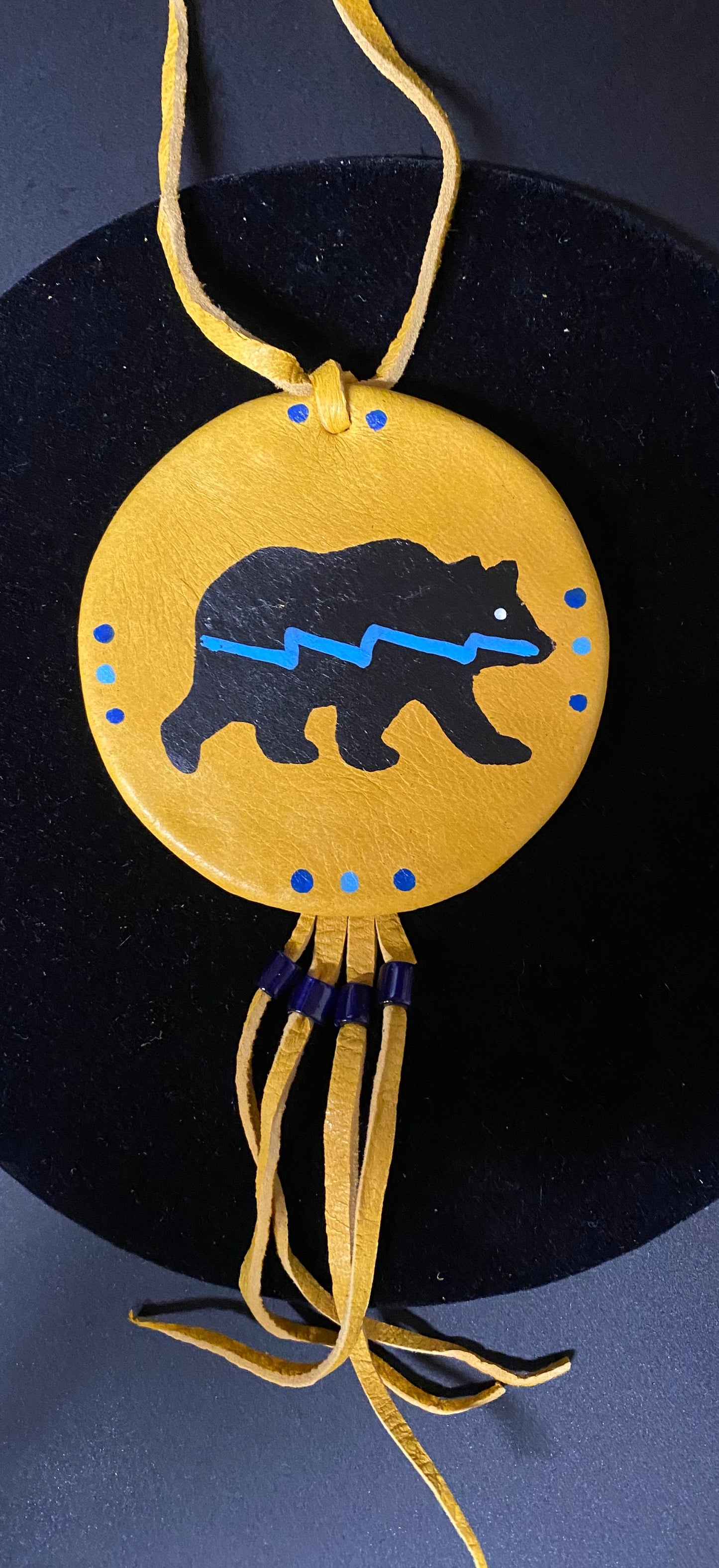 Decorative pendant with bear design on a dark background