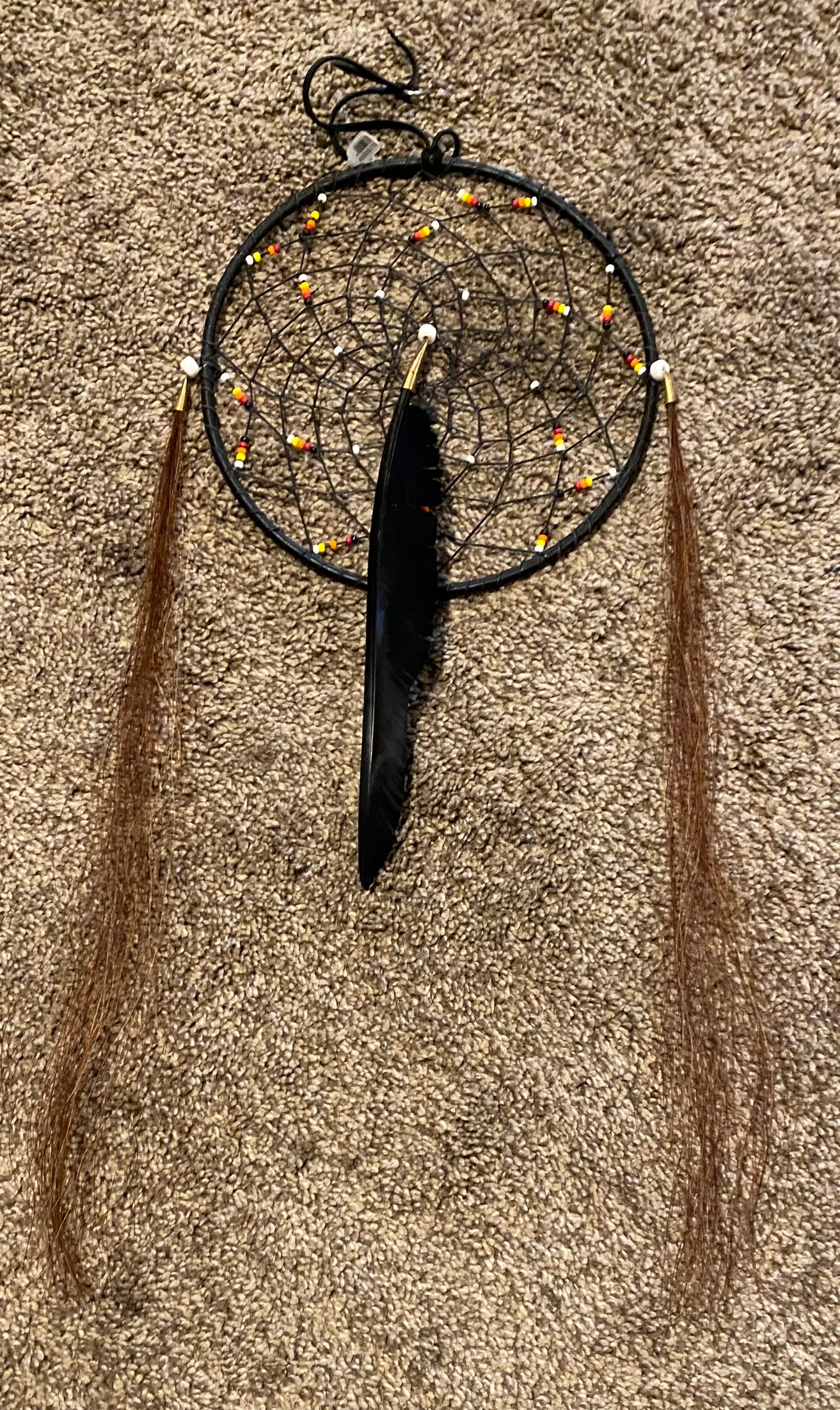 Black dreamcatcher with feathers on a textured surface