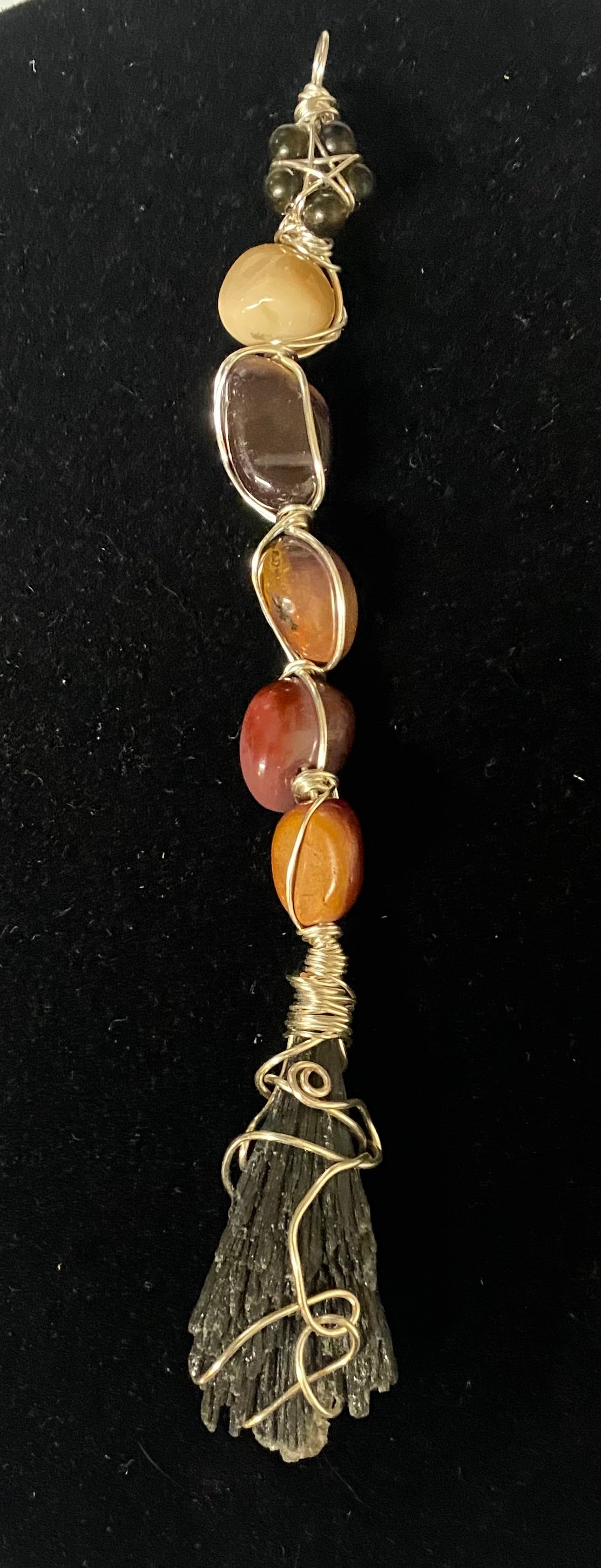 Decorative pendant with stones and wirework on a black background