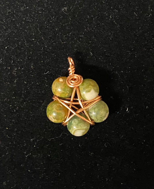 Ryolite beads pendant with copper wire wrapping on a black background