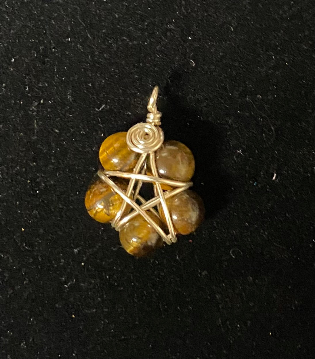 Pendant with tiger eye beads and gold wire wrapping on a black background