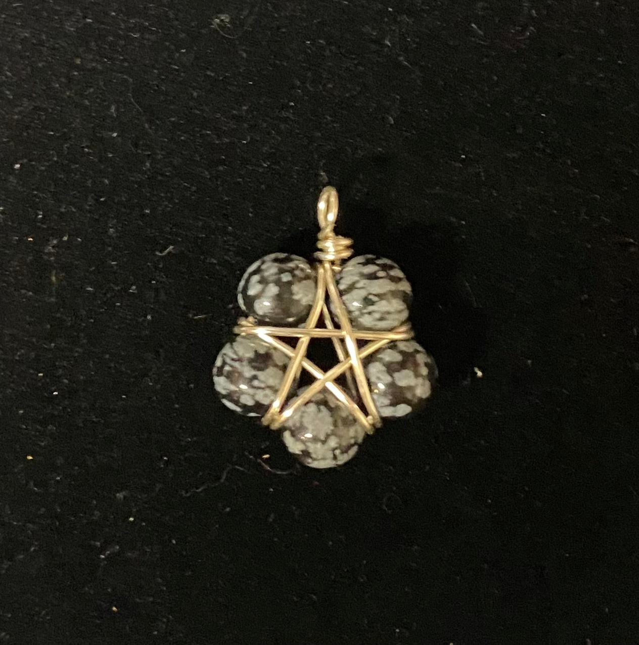 Pendant with snowflake obsidian stone beads and silver wire wrapping on a black background