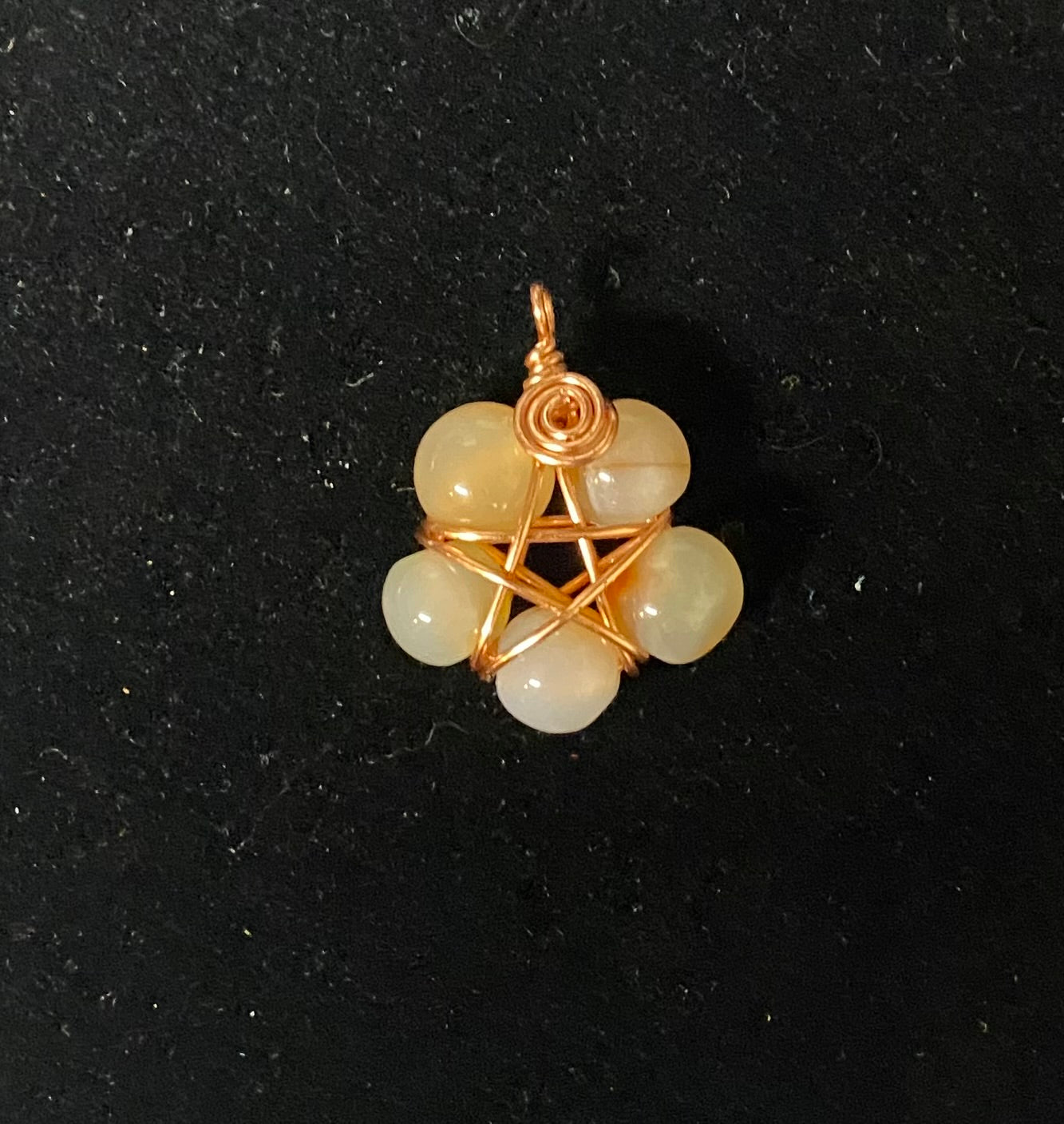 Pendant with copper wire wrapping and Fire agate beads on a black background