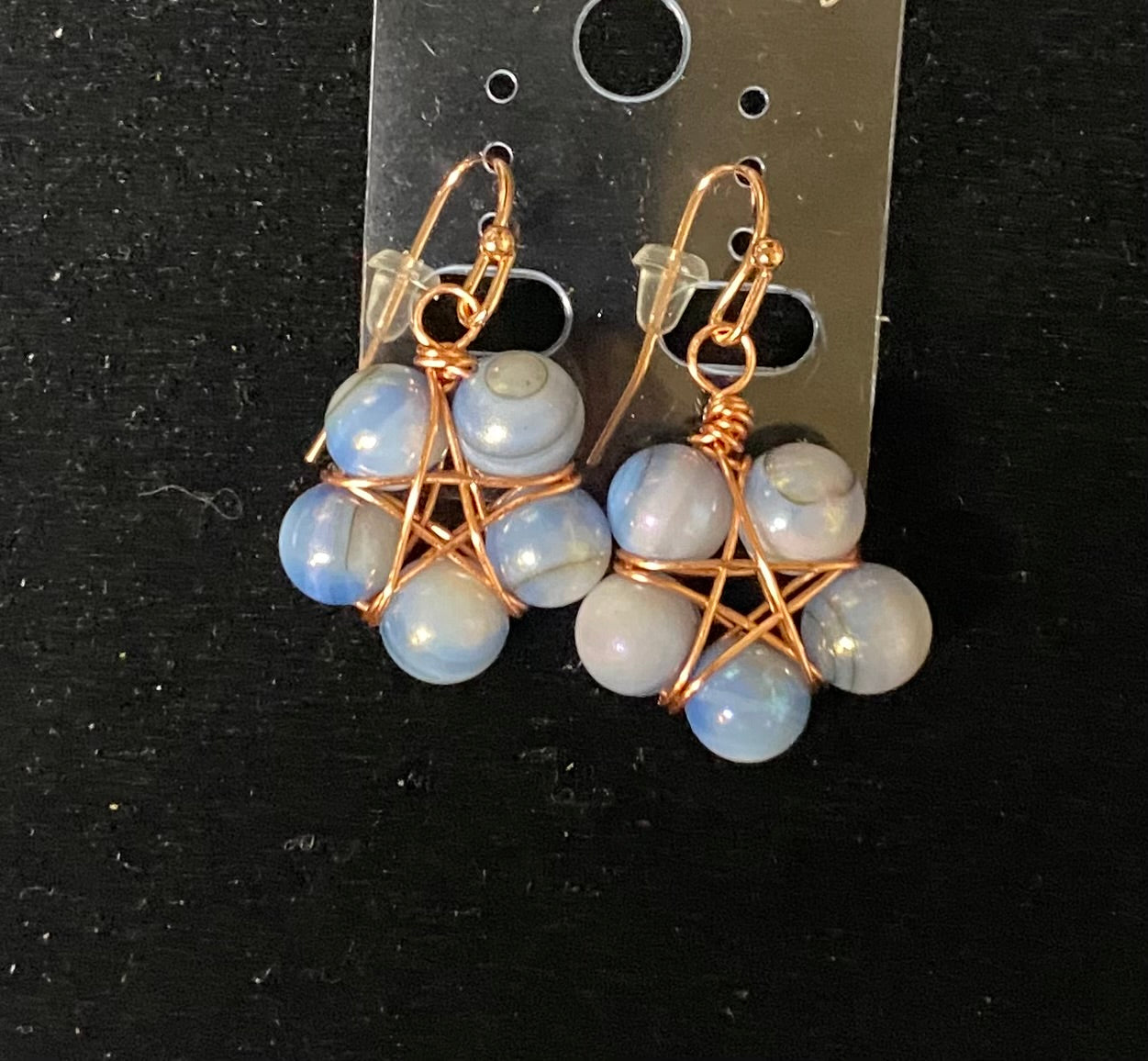 Pair of earrings with blue beads and gold wire wrapping on a black background