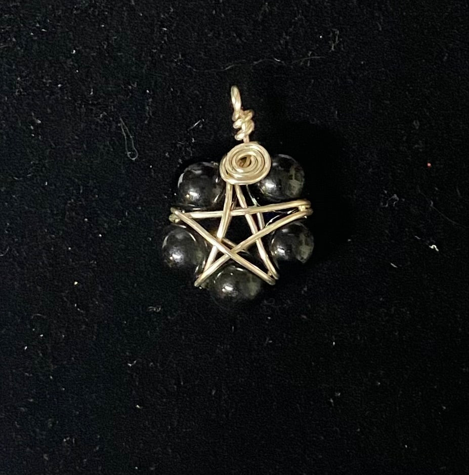 Pendant with star design and black beads on a black background