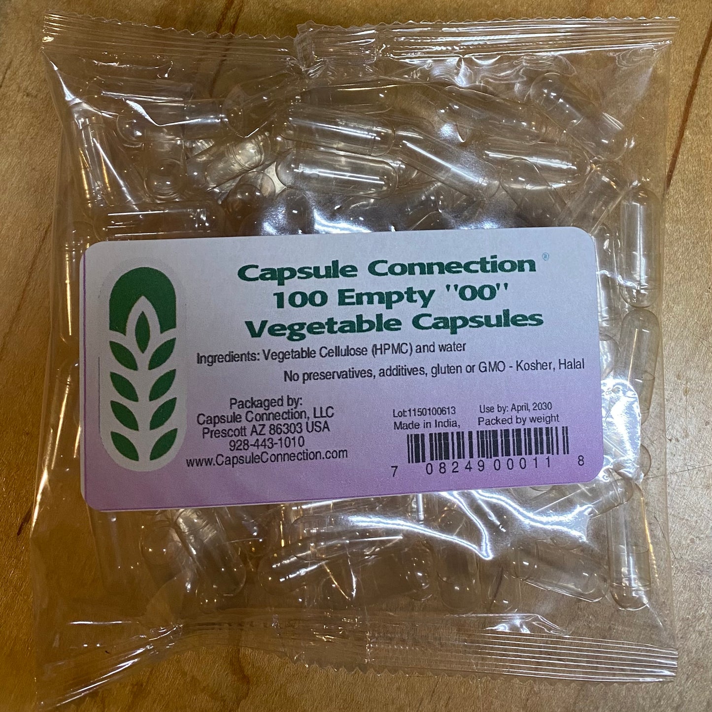 Pack of empty vegetable capsules with a 'Capsule Connection' label on a wooden surface.