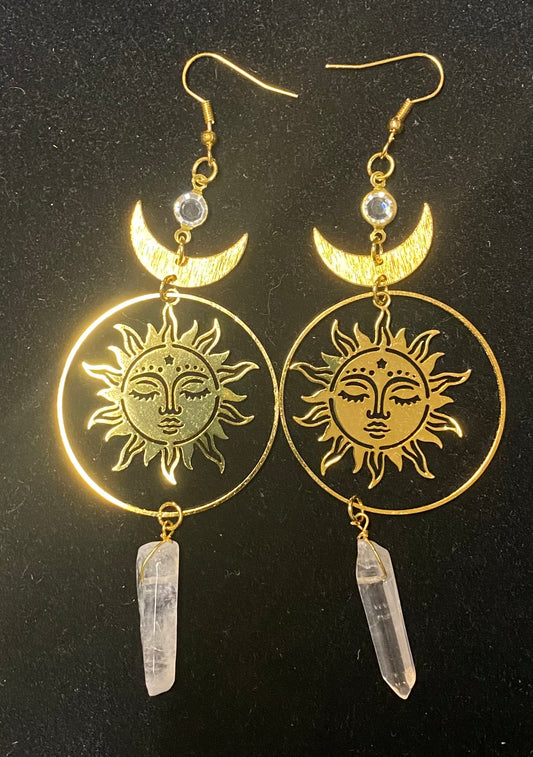 Gold sun and moon earrings with crystal pendants on a black background