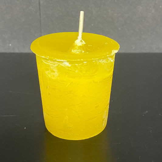 Yellow candle in a mold on a dark surface with a gray background