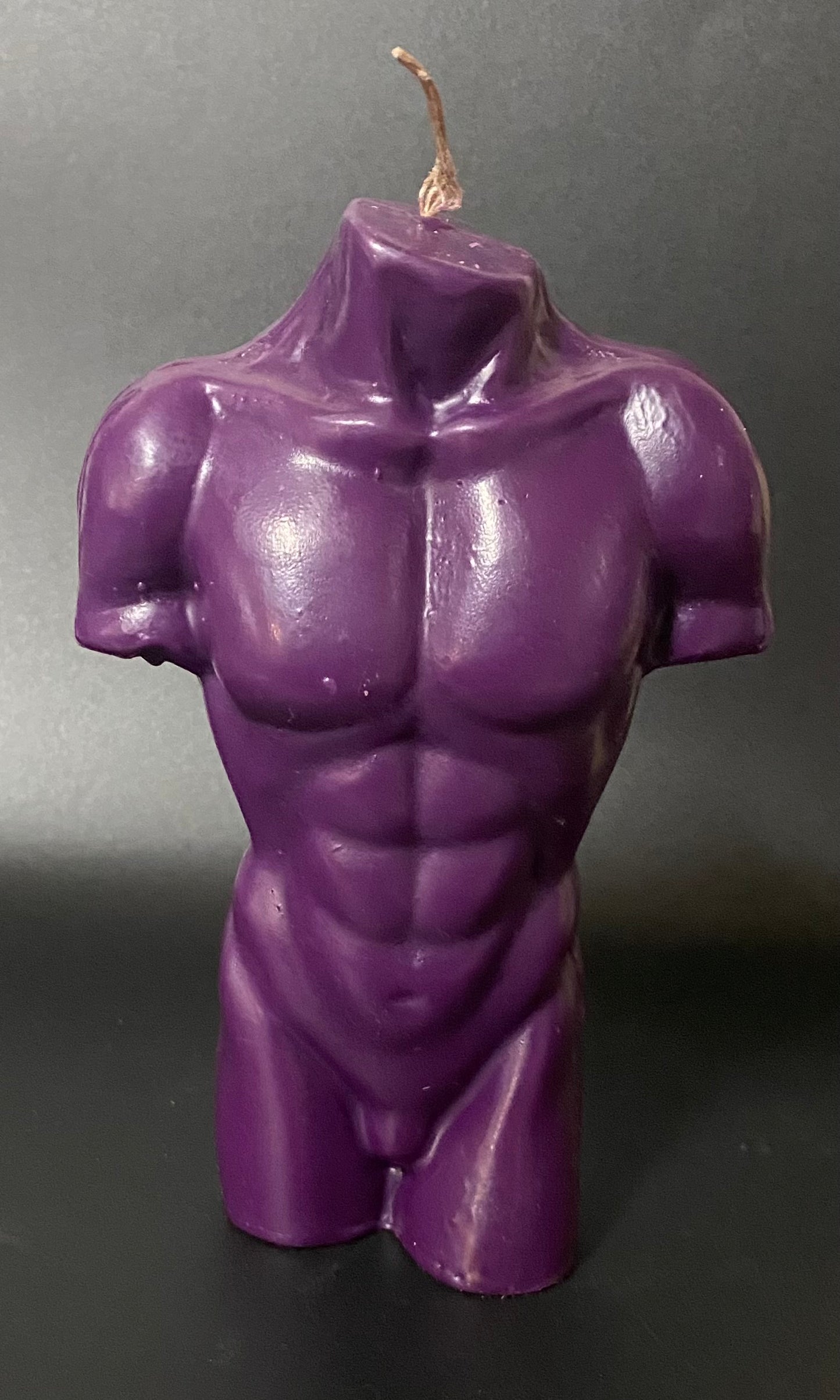 Purple muscular torso candle on a dark background