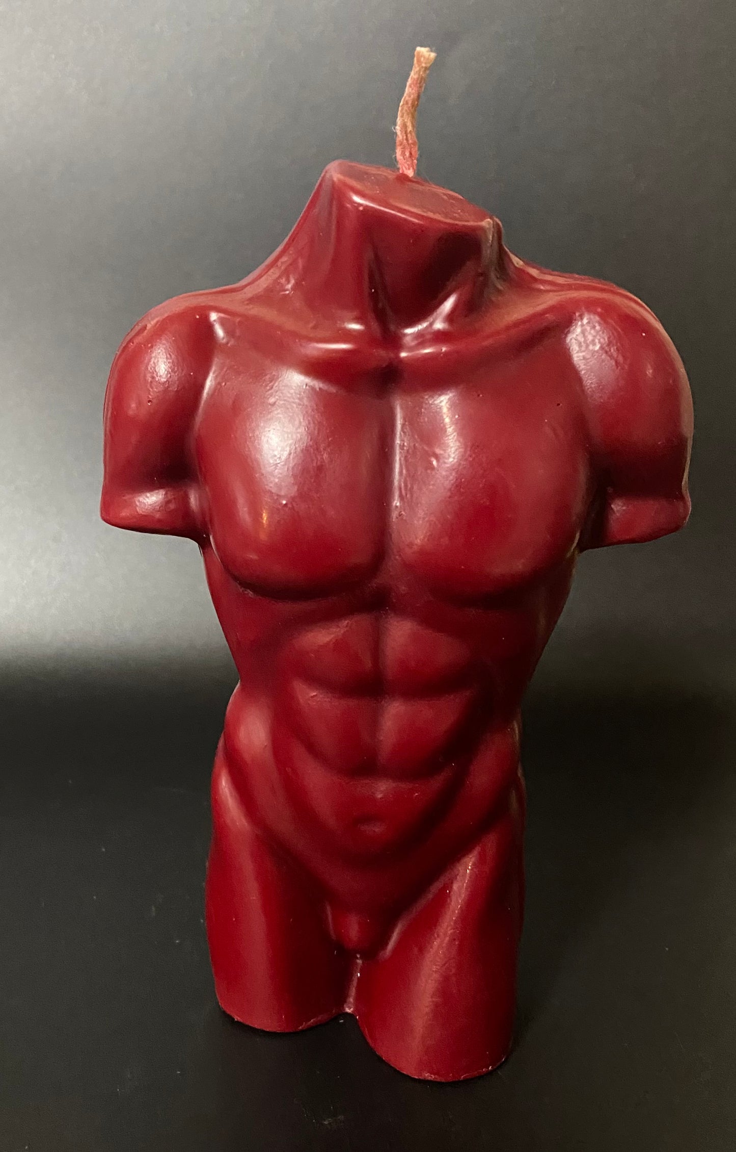 Red muscular torso candle on a dark background