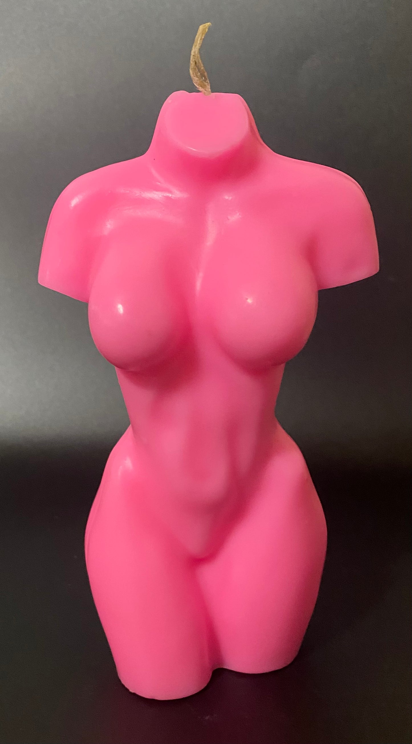 Pink candle shaped like a female torso on a dark background