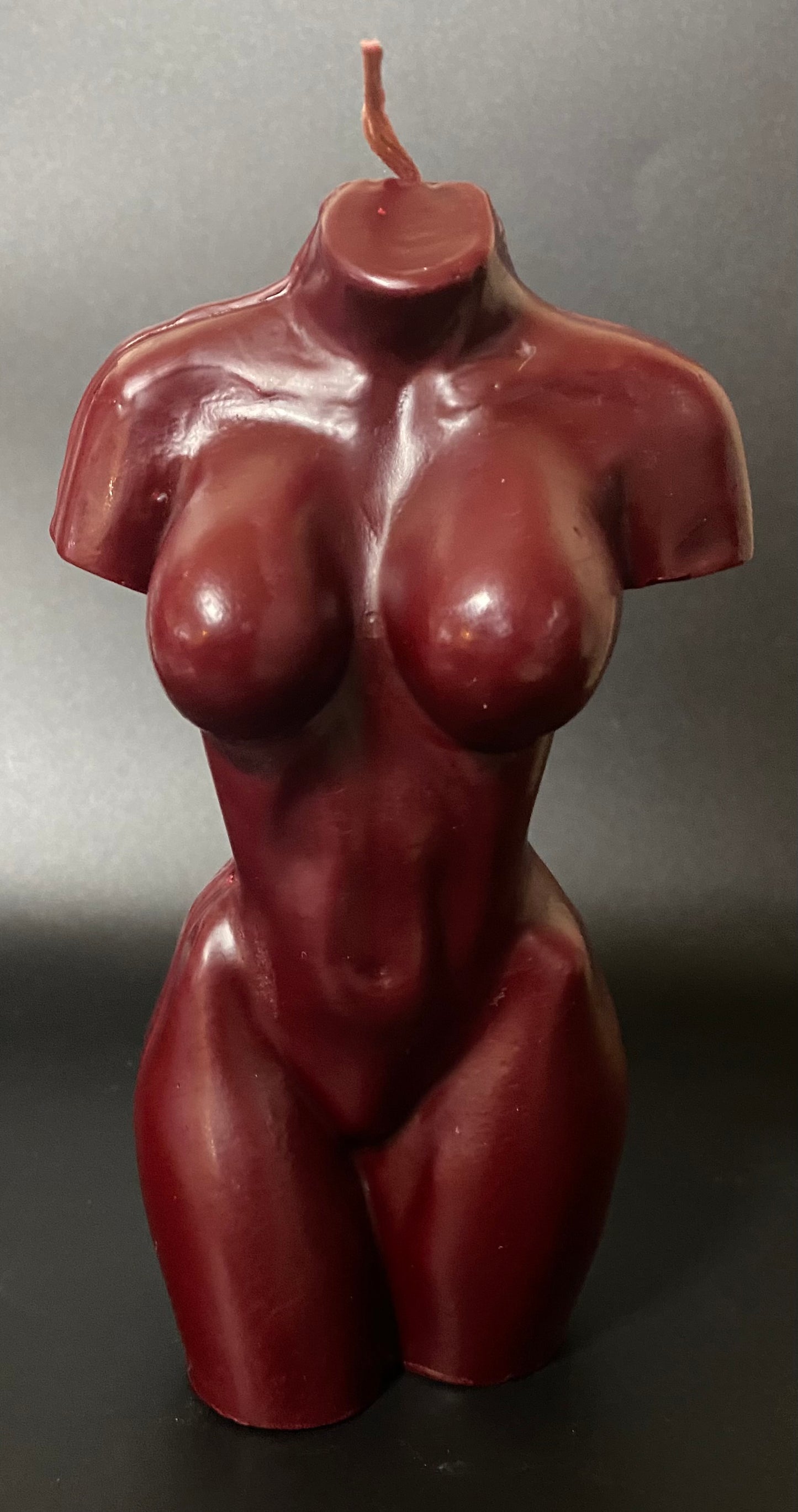 Red-brown candle shaped like a human torso on a gray background