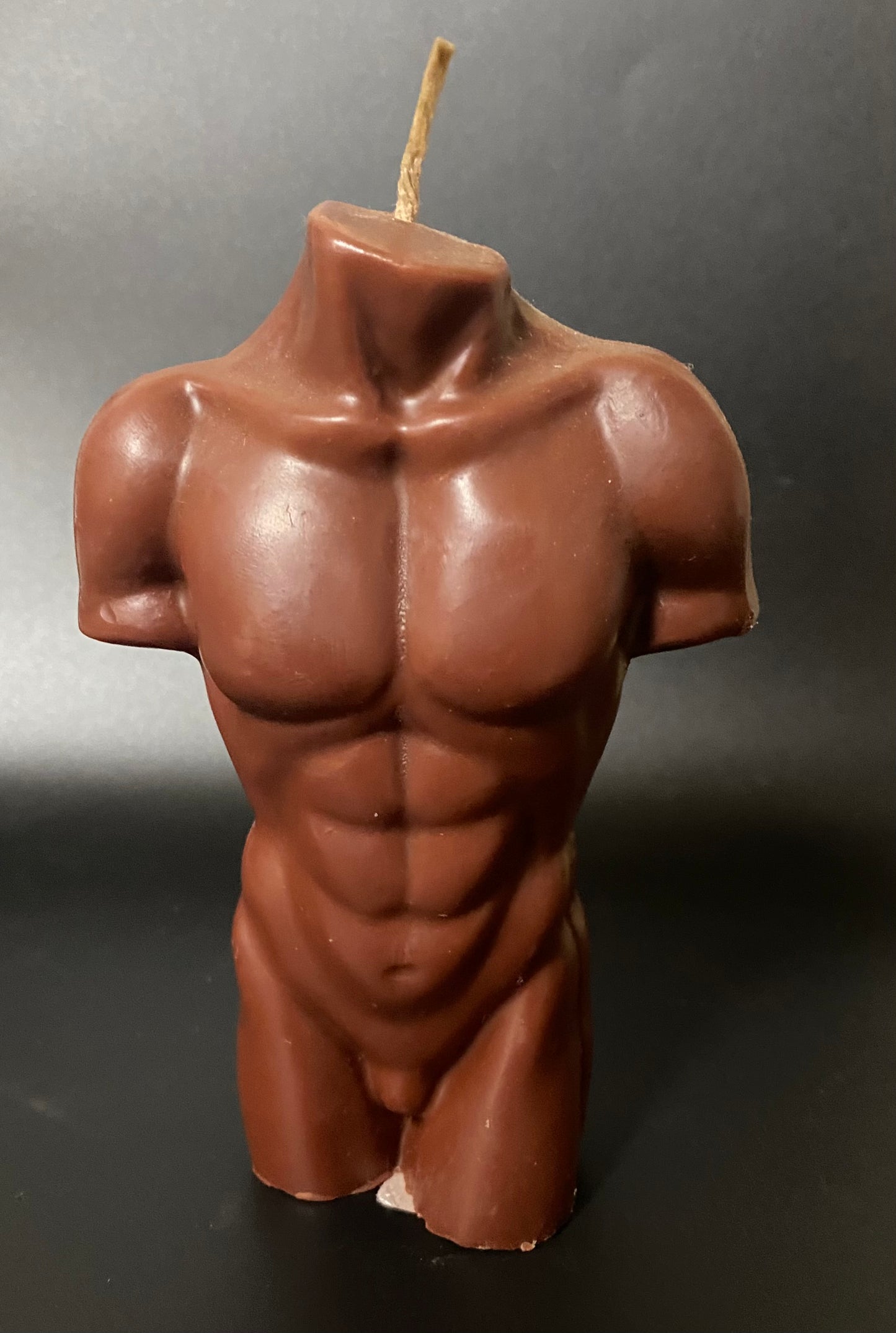 Candle Brown of a muscular torso on a dark background