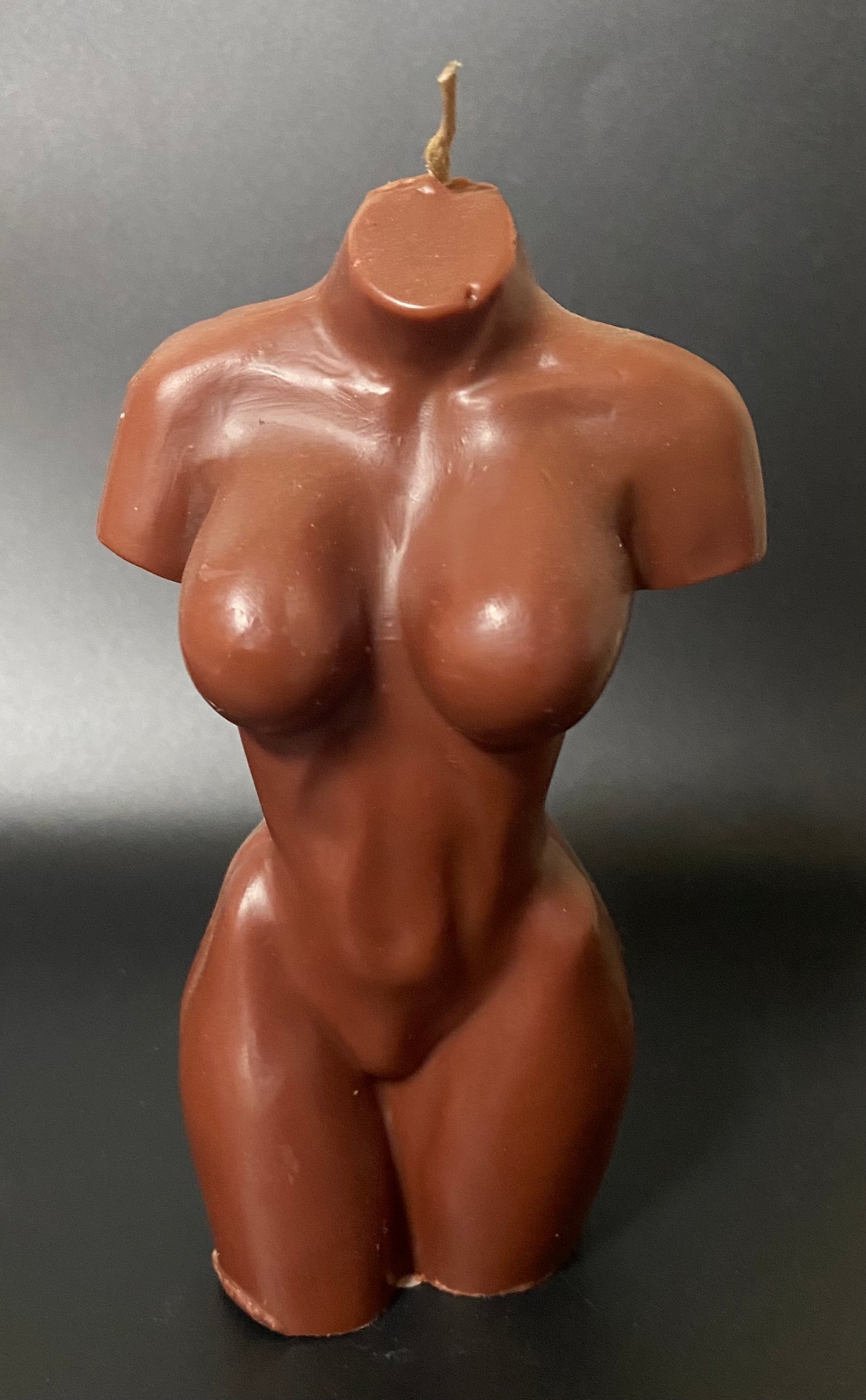 Brown female torso candle on a gray background