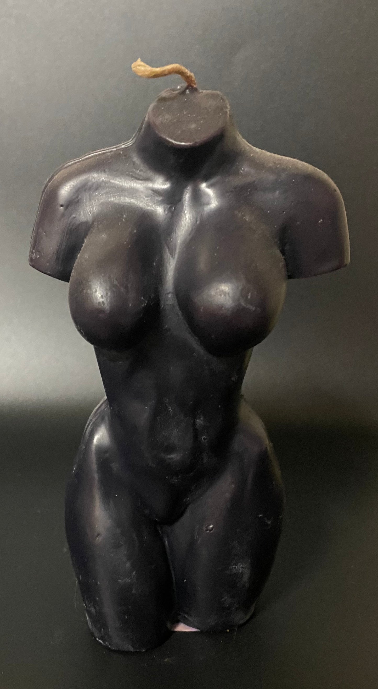 Black female torso candle on a dark background
