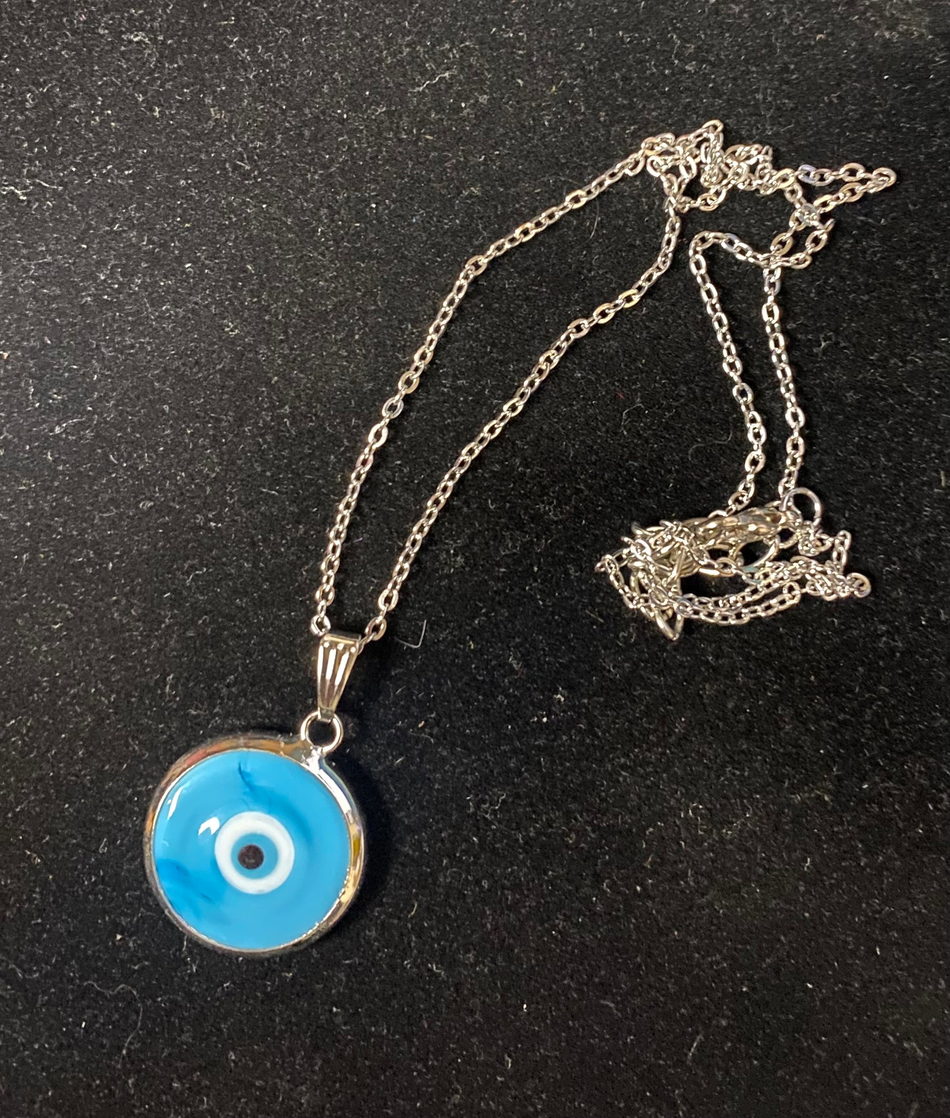 Necklace with a blue evil eye pendant on a black background