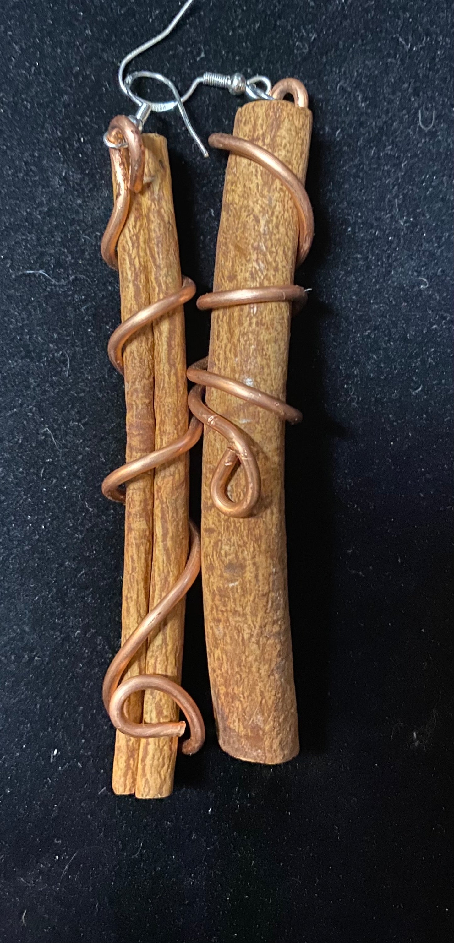 Cinnamon stick earrings with copper on a black background