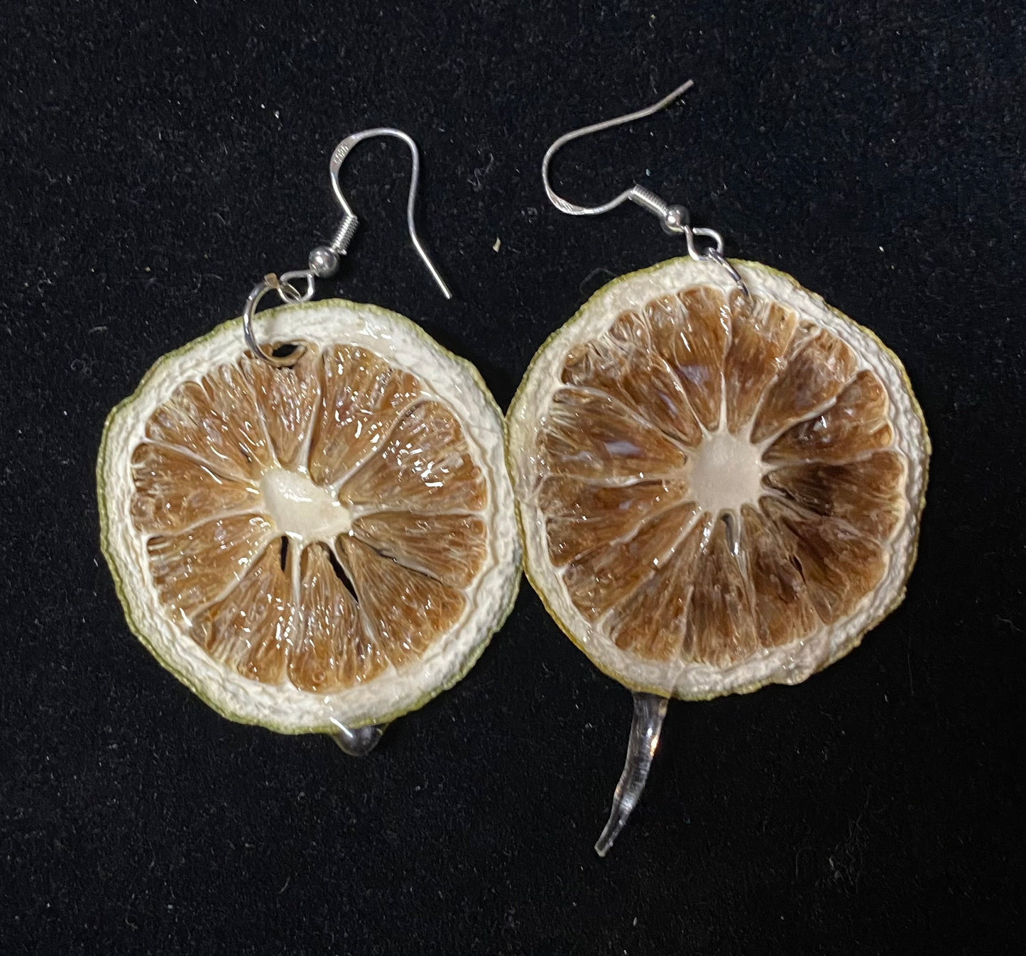 Earrings made from dried lime slices on a black background