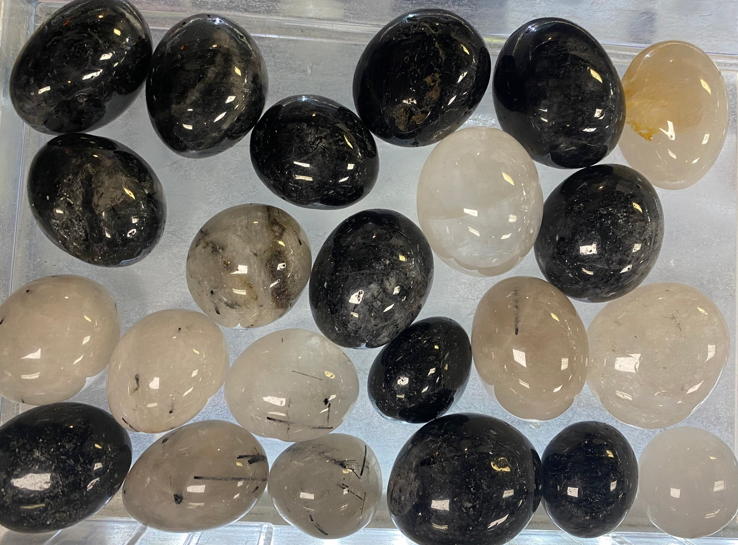 Collection of black and beige stones in a clear container