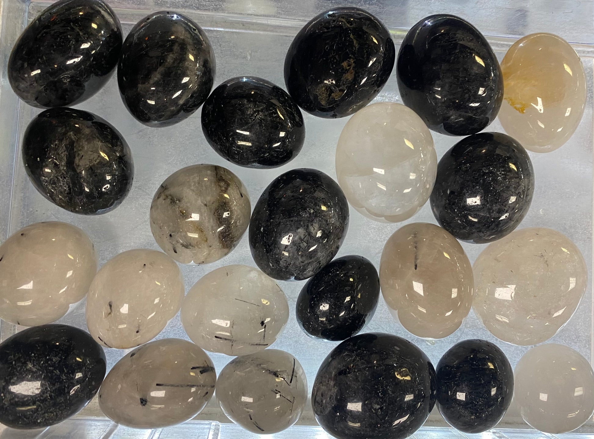 Collection of black and beige stones in a clear container