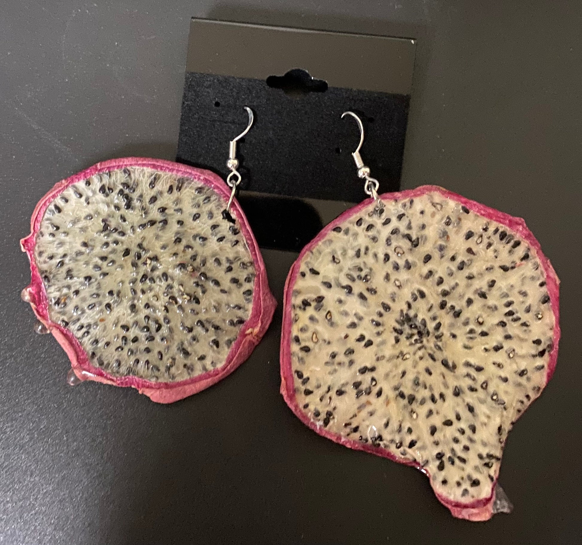 Dragon fruit slice earrings on a dark surface