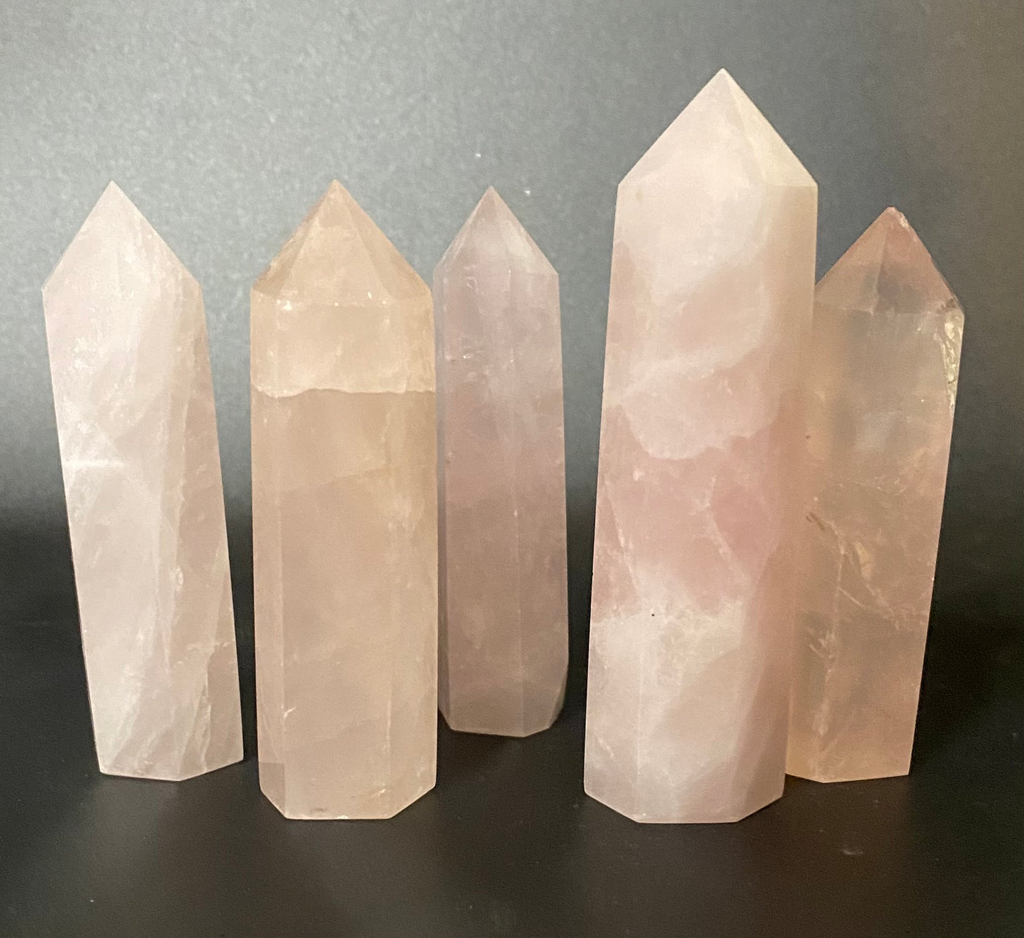 Five crystal towers of varying heights on a dark surface with a gray background