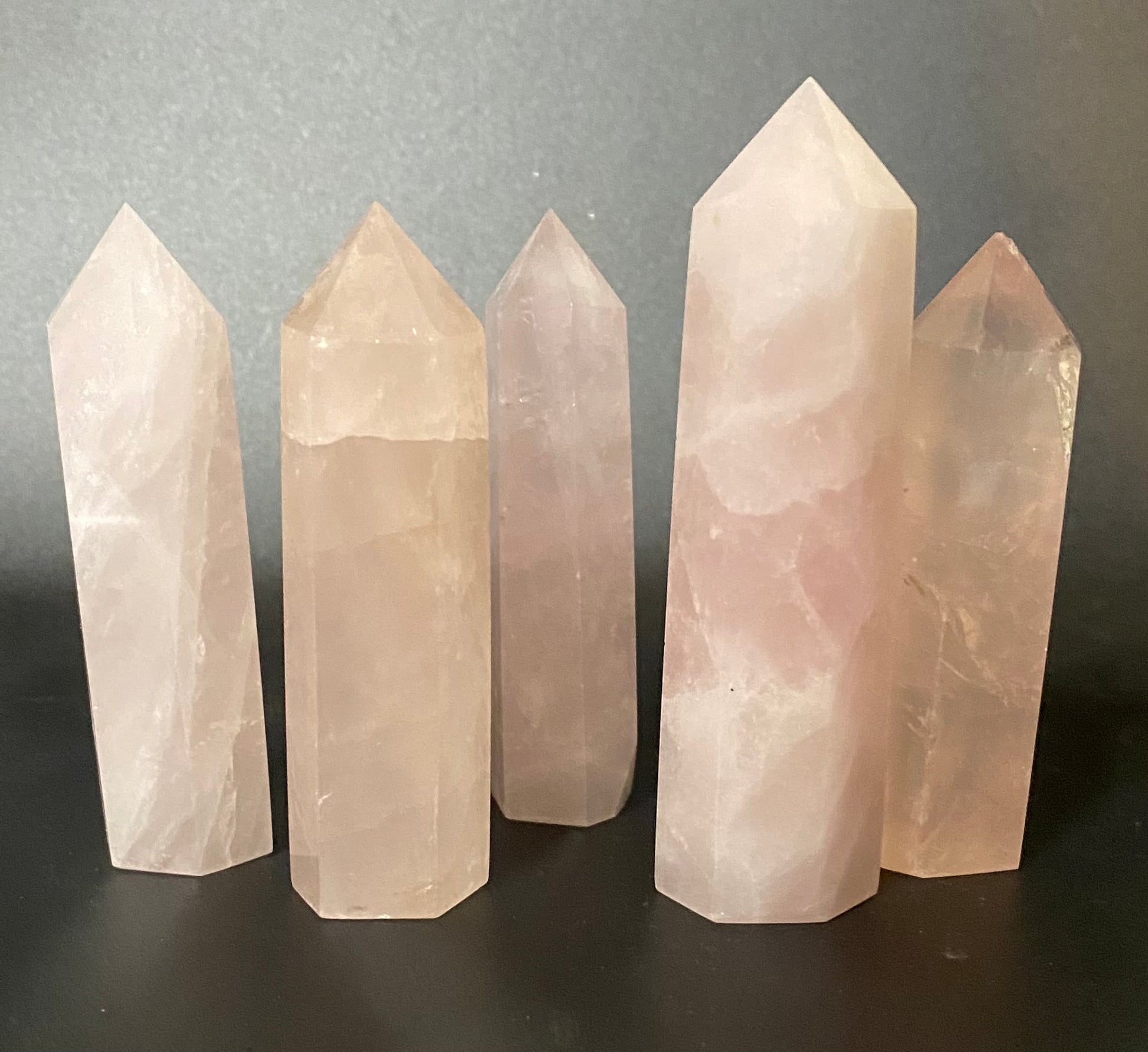 Five crystal towers of varying heights on a dark surface with a gray background
