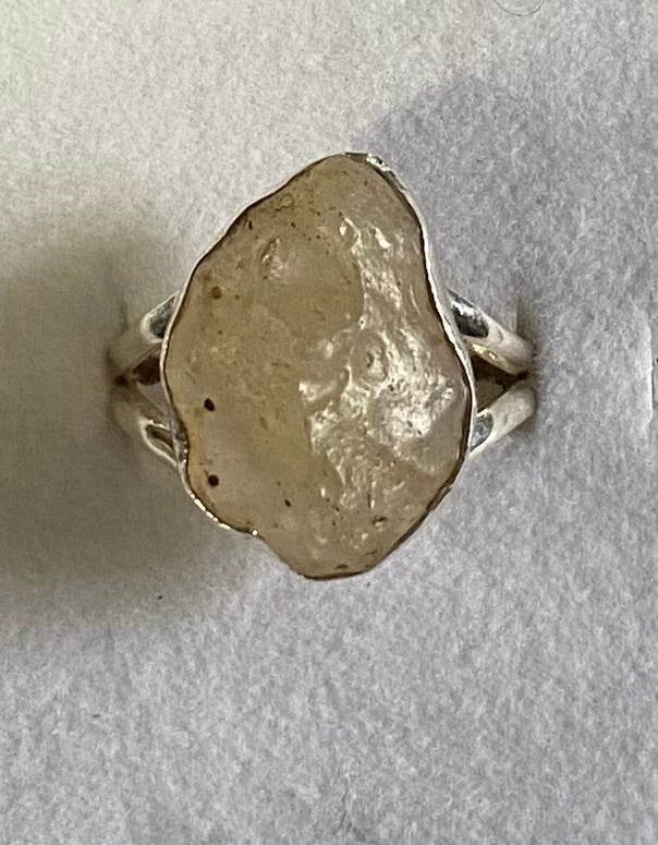 Silver ring with a large, rough-textured stone on a light gray background