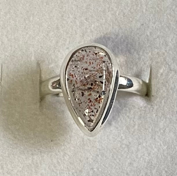 Silver ring with a teardrop-shaped stone on a light gray background