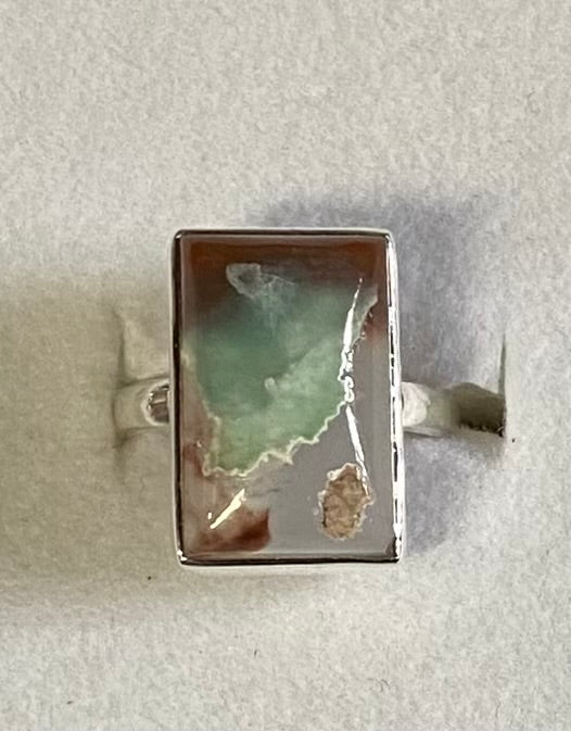 Silver ring with a rectangular stone on a light gray background