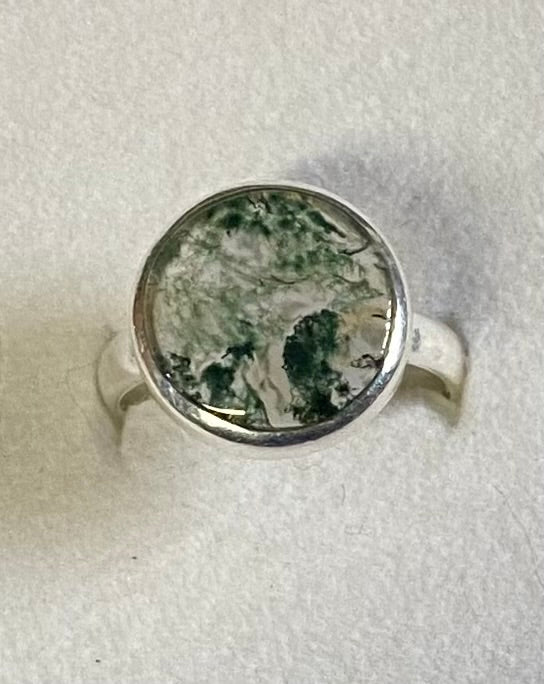 Silver ring with a green stone on a white background