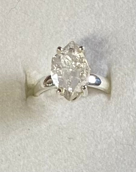Silver ring with a large diamond on a light gray background