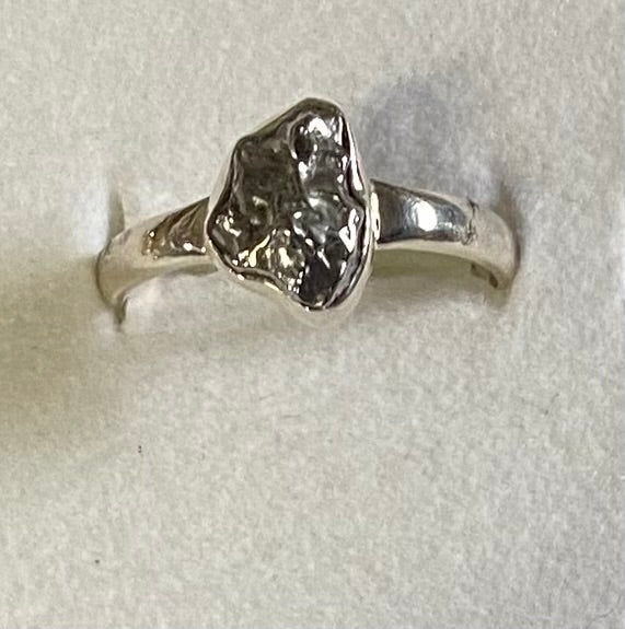 Silver ring with a rough diamond-like stone on a light gray background