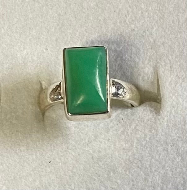 Silver ring with a green stone on a light gray background
