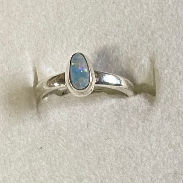 Silver ring with an opal stone on a light gray background
