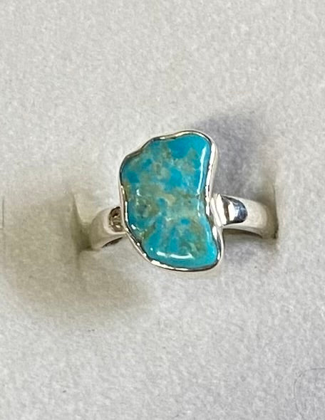 Silver ring with a turquoise stone on a light gray background