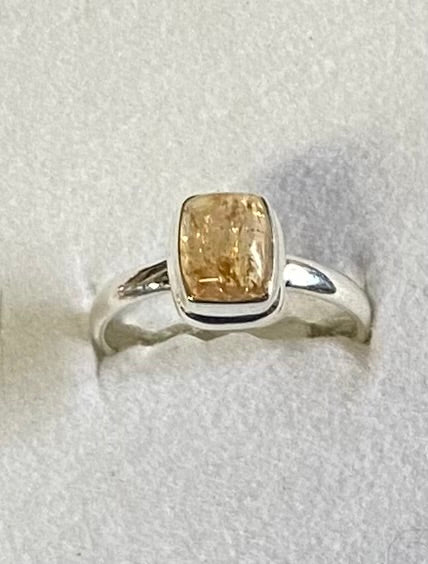 Silver ring with a yellow gemstone on a light gray background