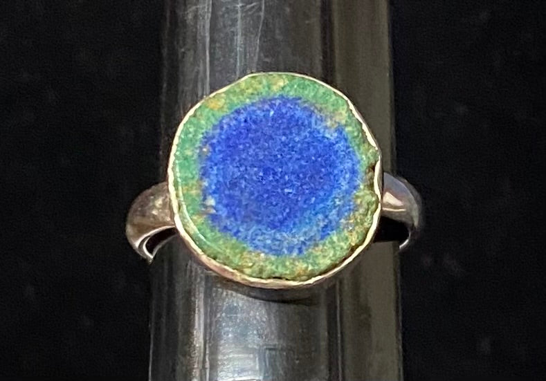 Ring with blue stone and gold rim on a black background