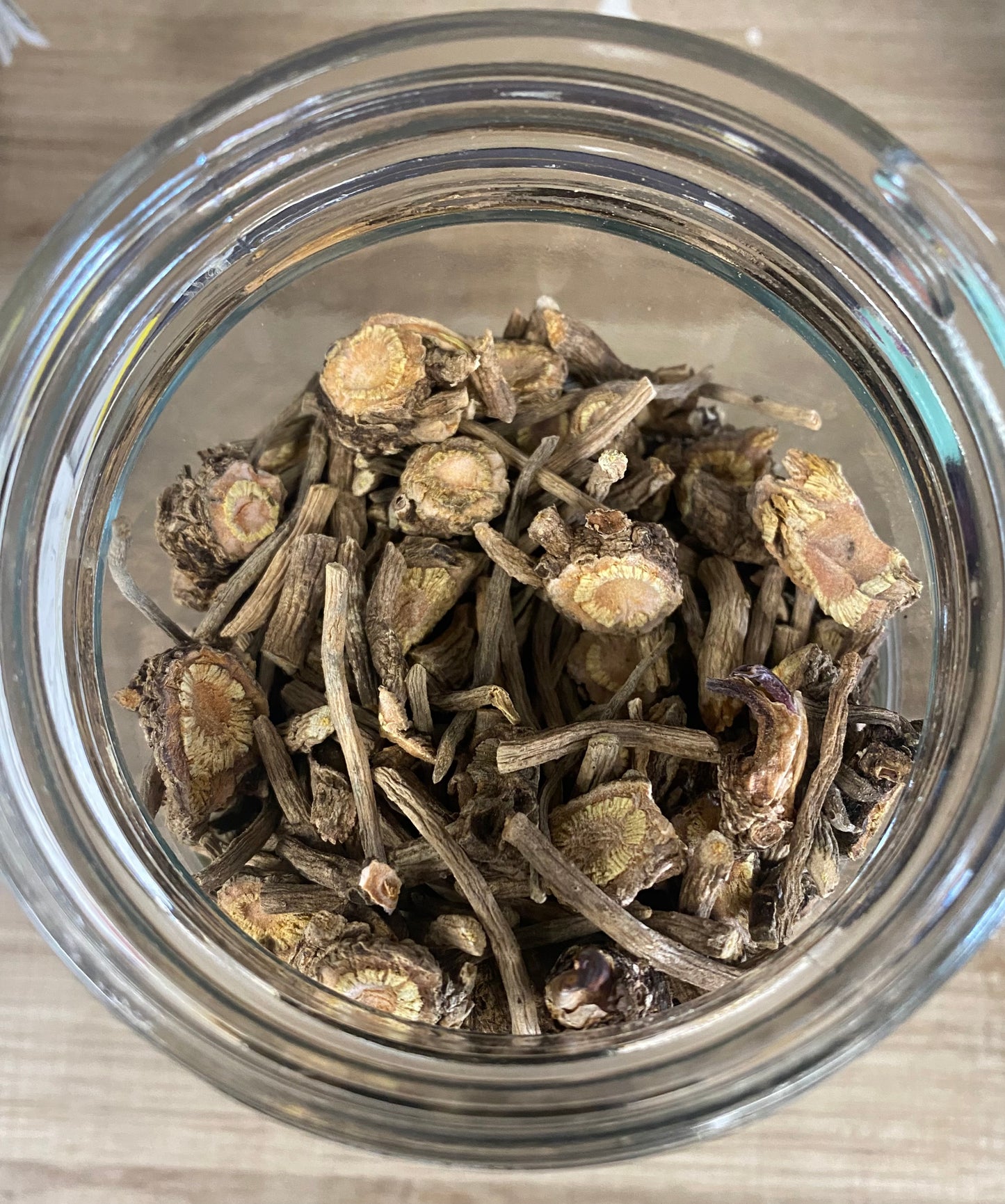 Glass jar filled with dried herbs on a wooden surface