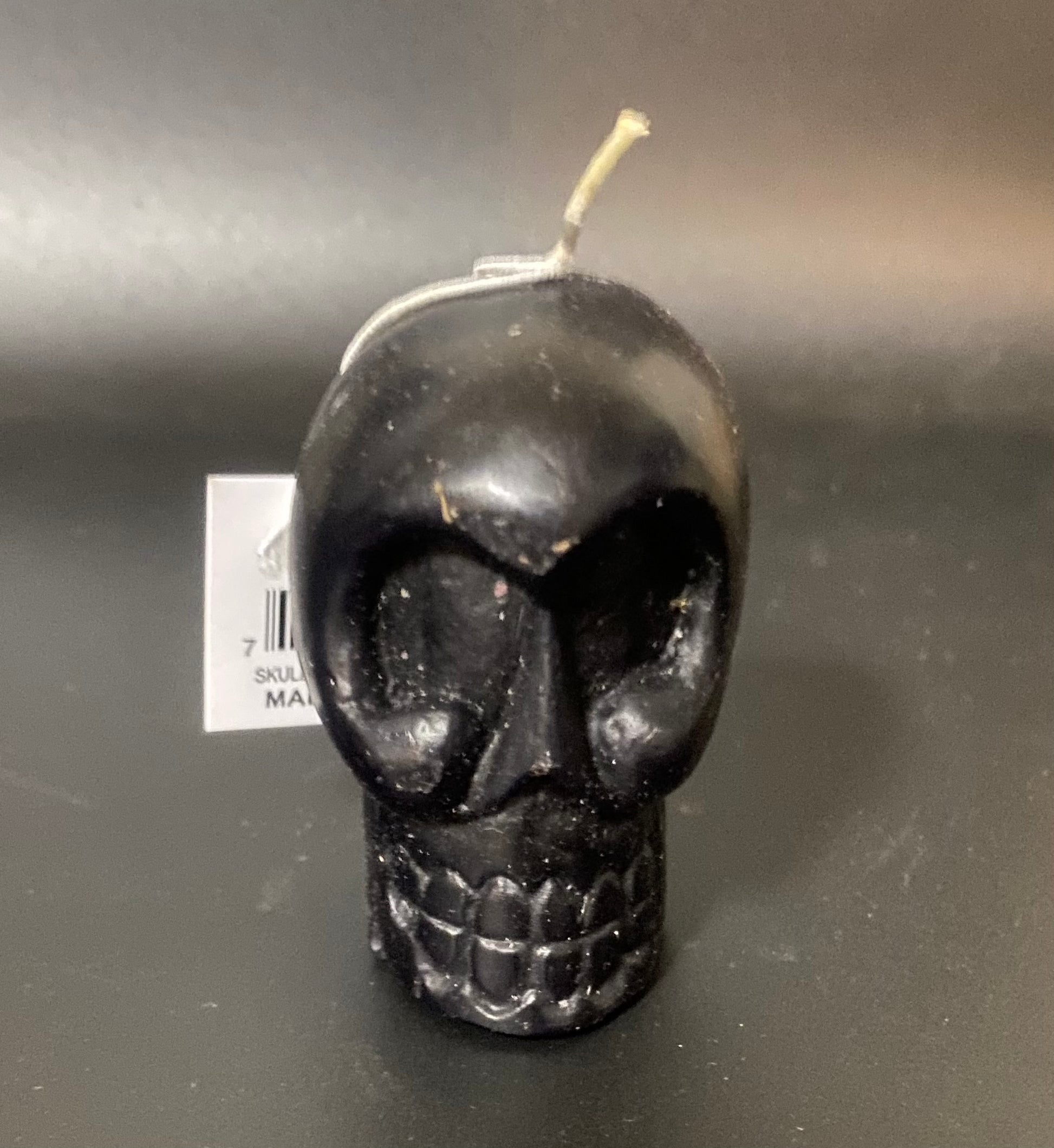 Black skull-shaped candle on a dark surface