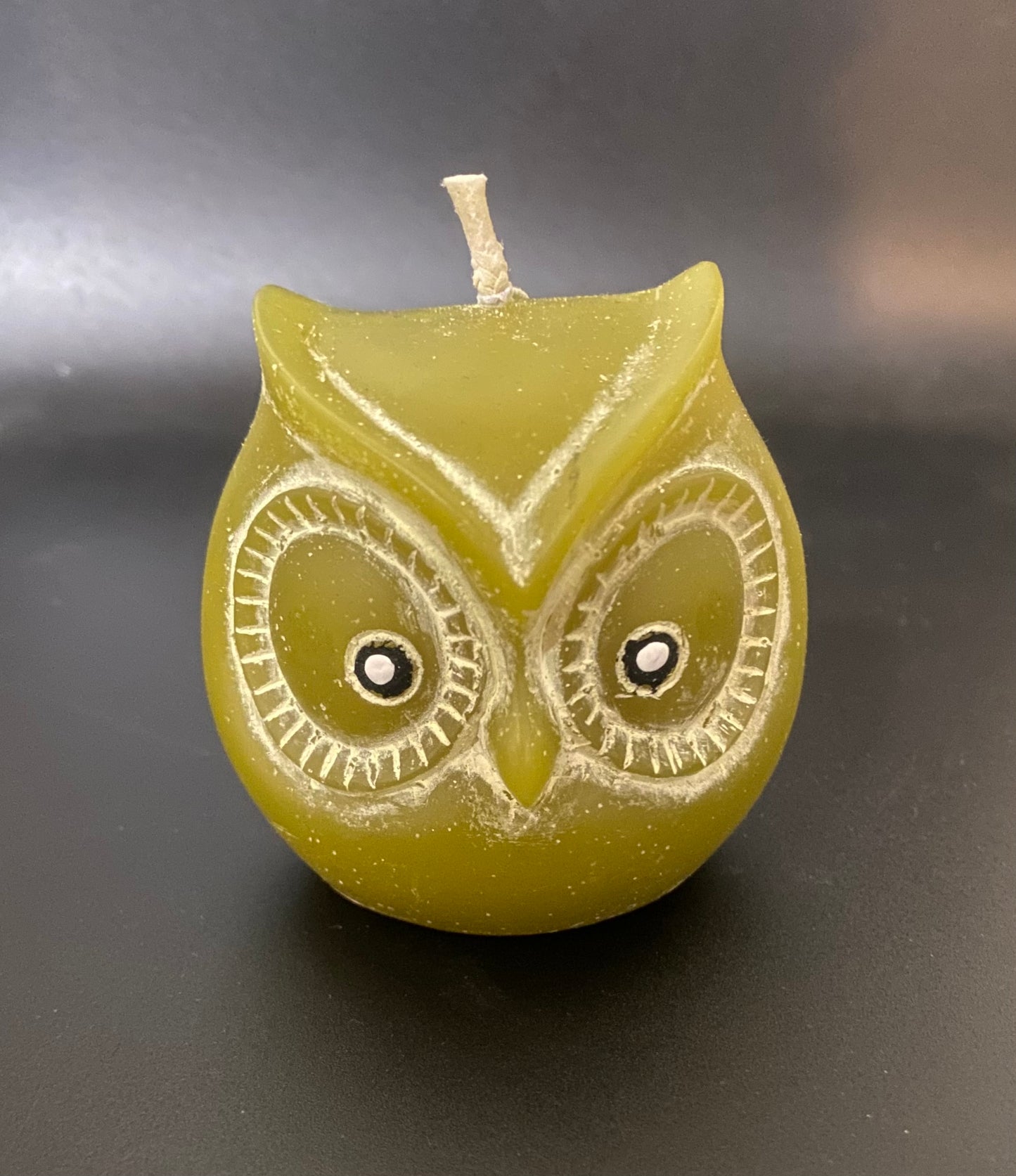 Green owl-shaped candle on a dark background
