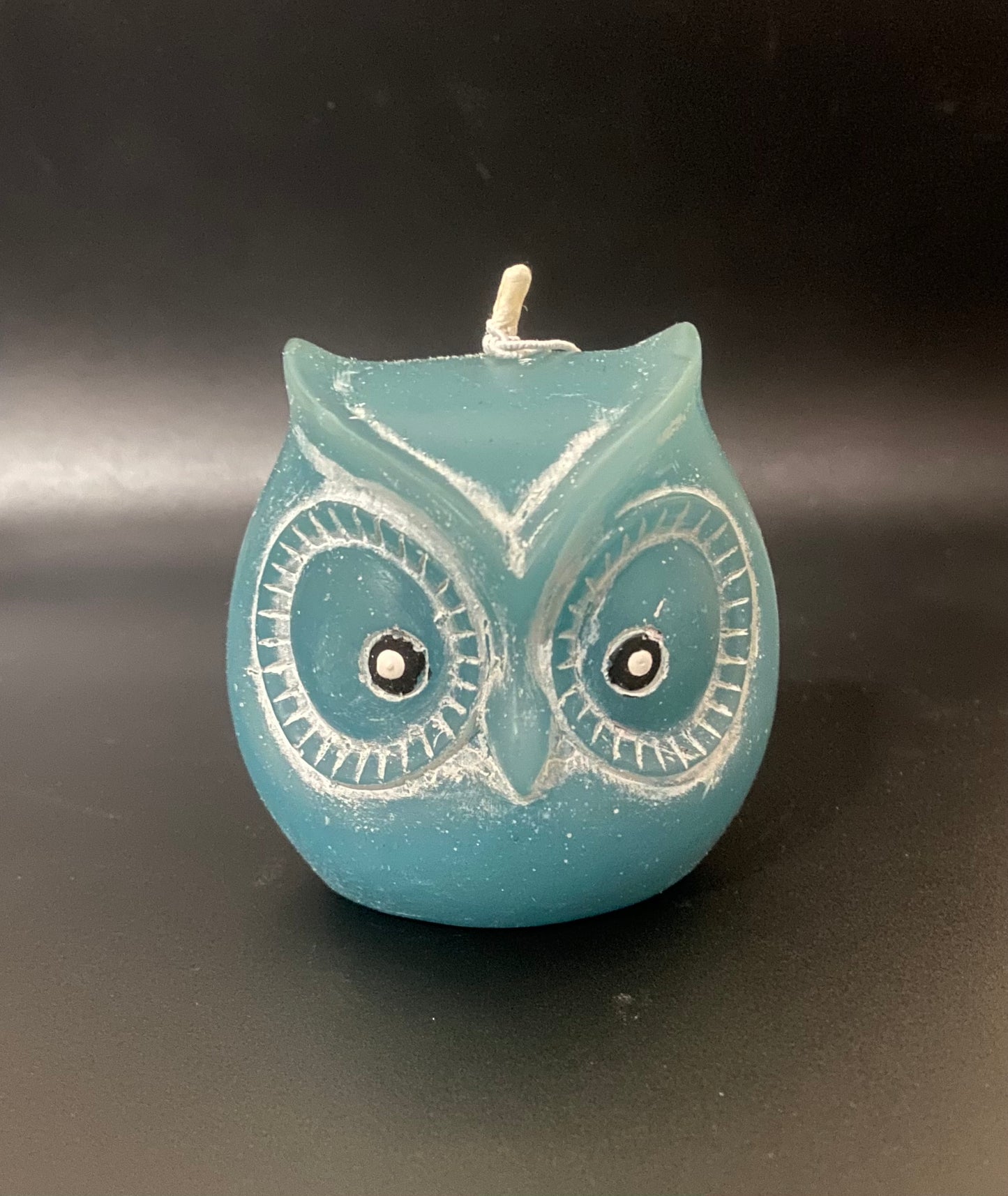 Blue owl-shaped candle on a dark background
