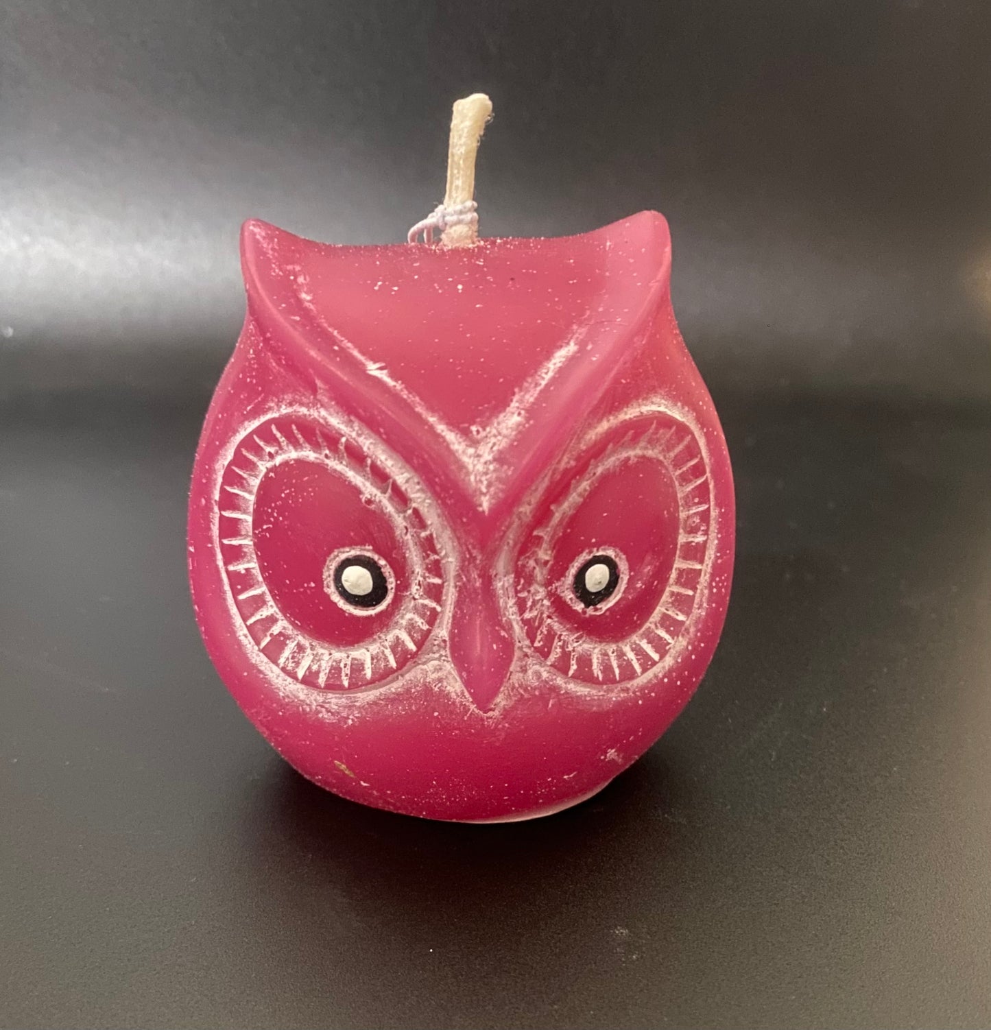 Pink owl-shaped candle on a dark background
