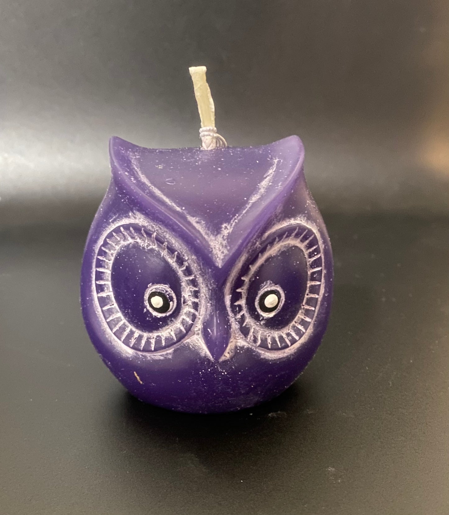 Purple owl-shaped candle on a dark background