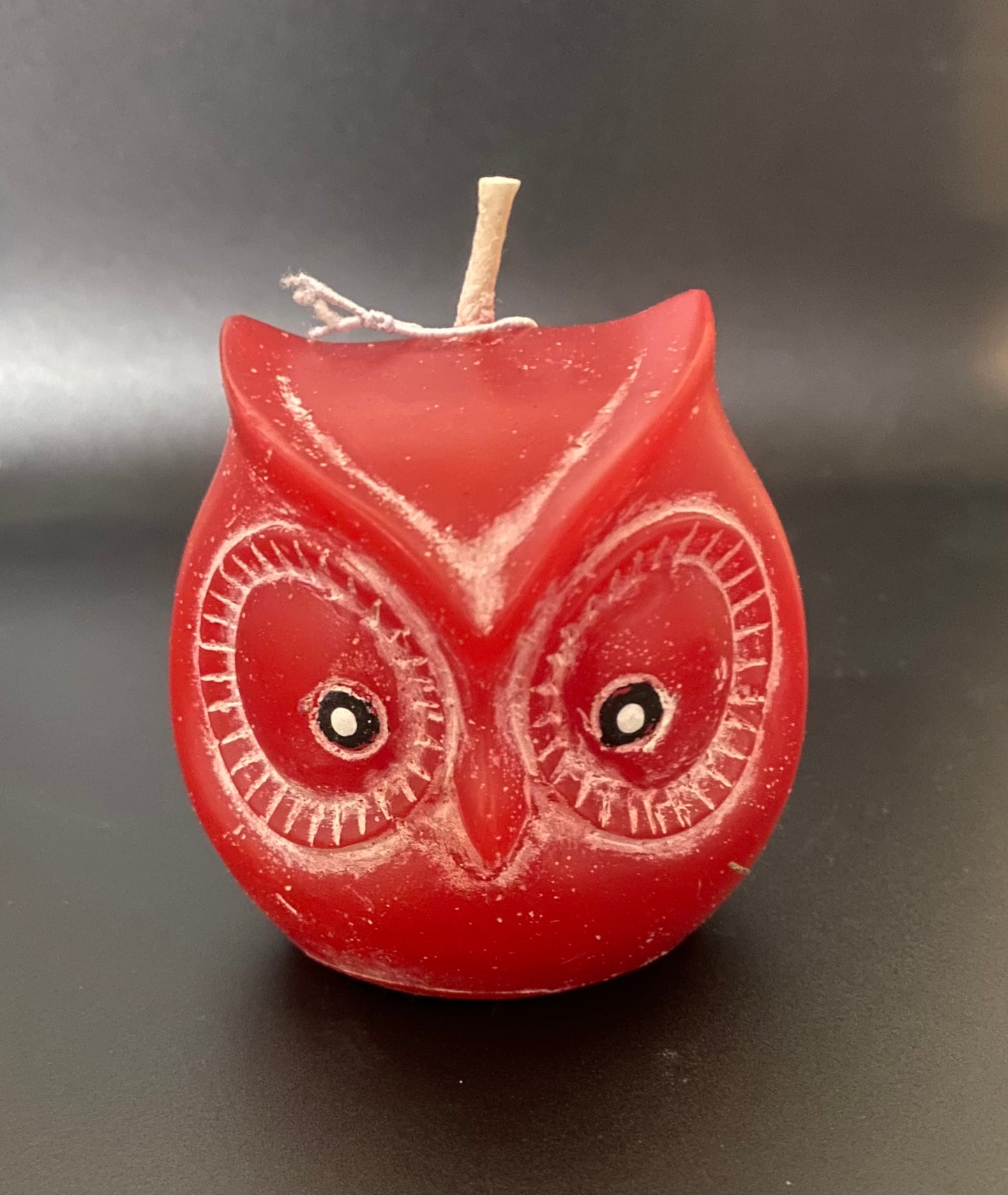 Red owl-shaped candle on a dark background