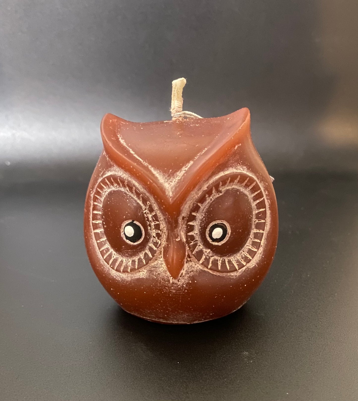 Brown owl-shaped candle on a dark background