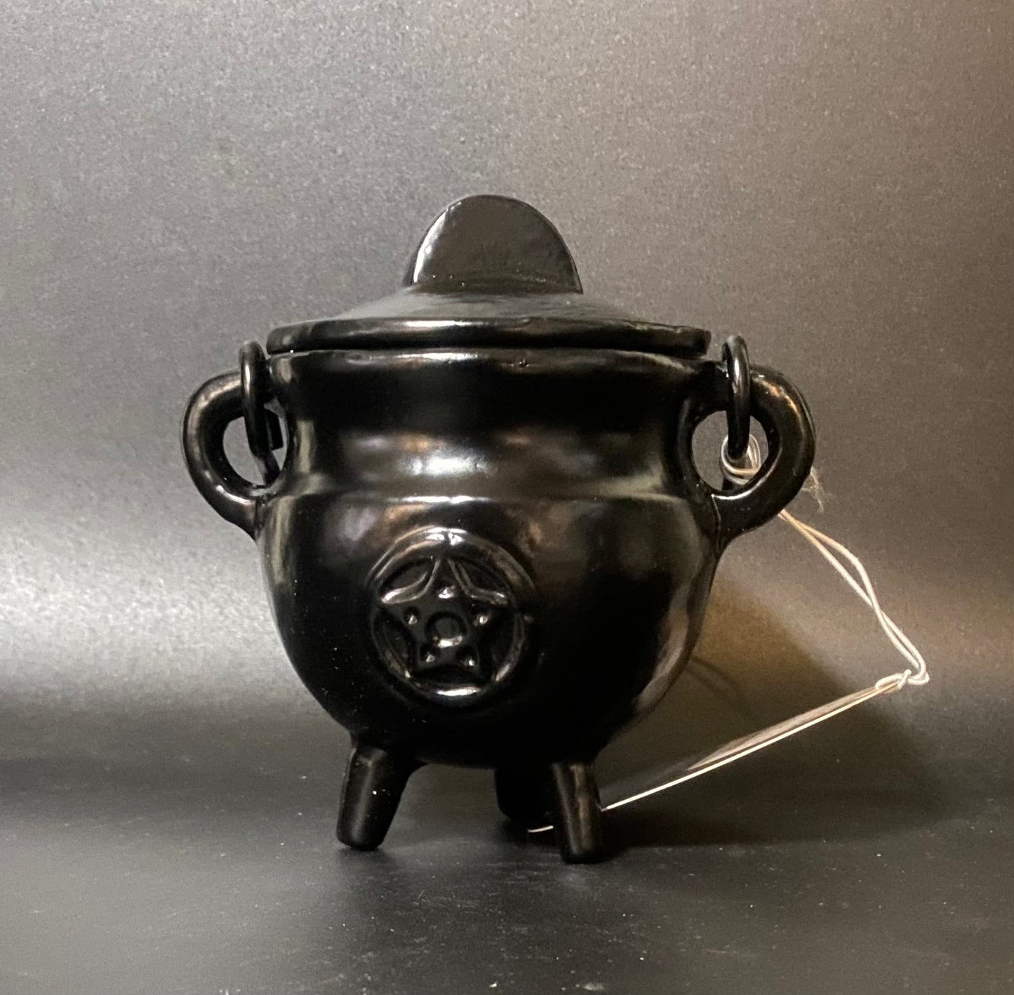 Black Iron cauldron candle with a string on a gray background